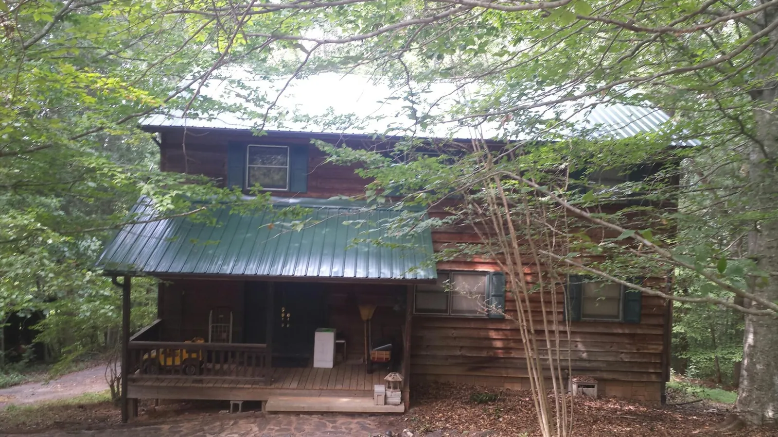 Green metal roof and covered porch on a log cabin in Kendallville