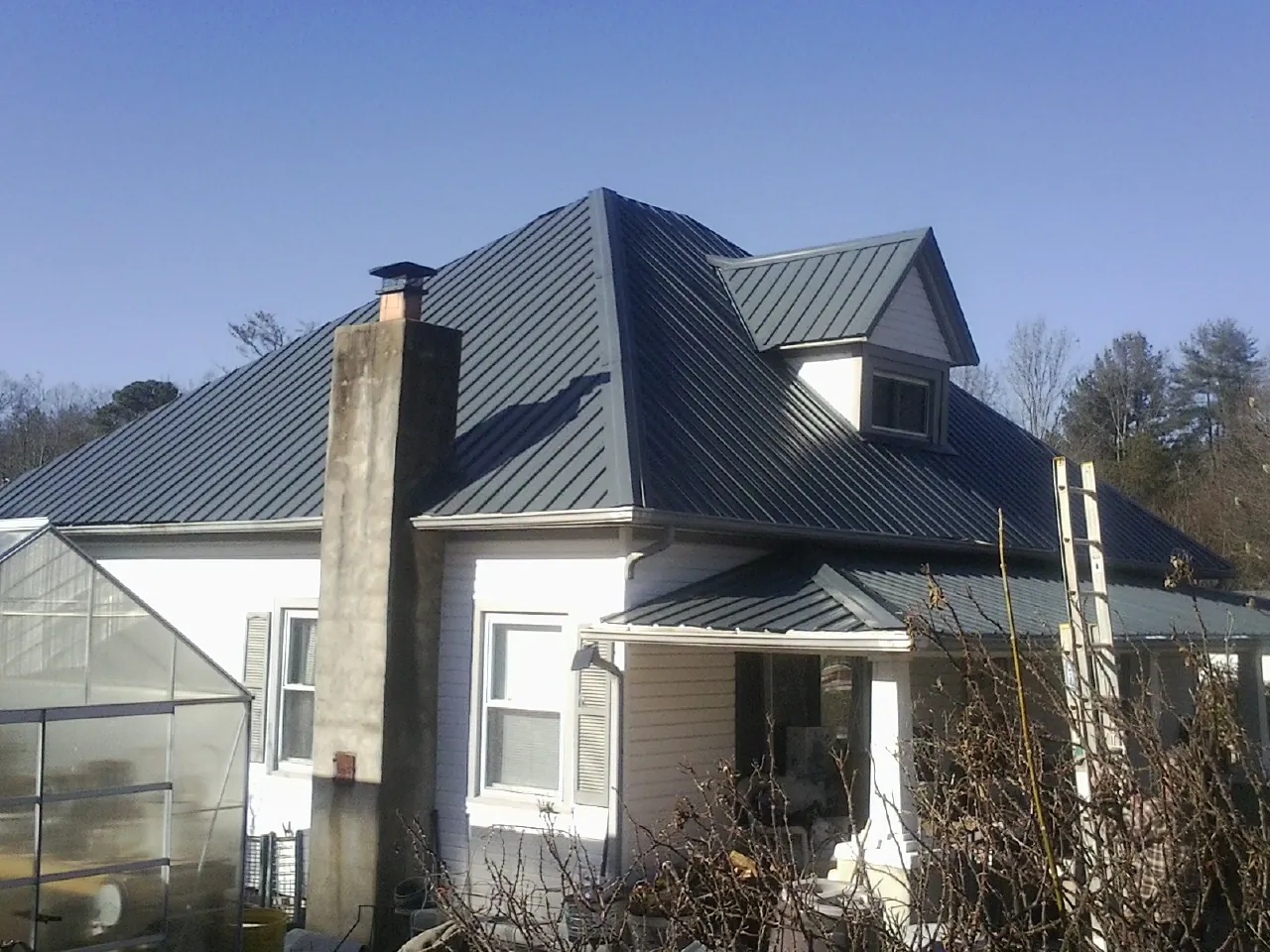 Dark blue standing seam metal roof on a white farmhouse with dormer — Slate & Tile Roof Repair by Roofing Brothers in Kendallville