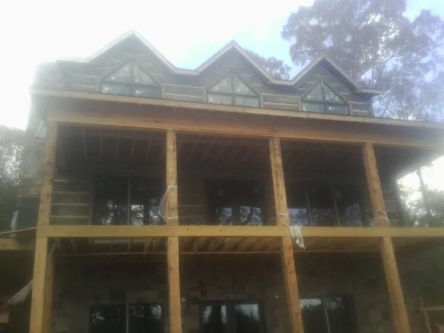 Dormers and porch framing on a large log home under construction — Roof Coating work by our crew in Kendallville