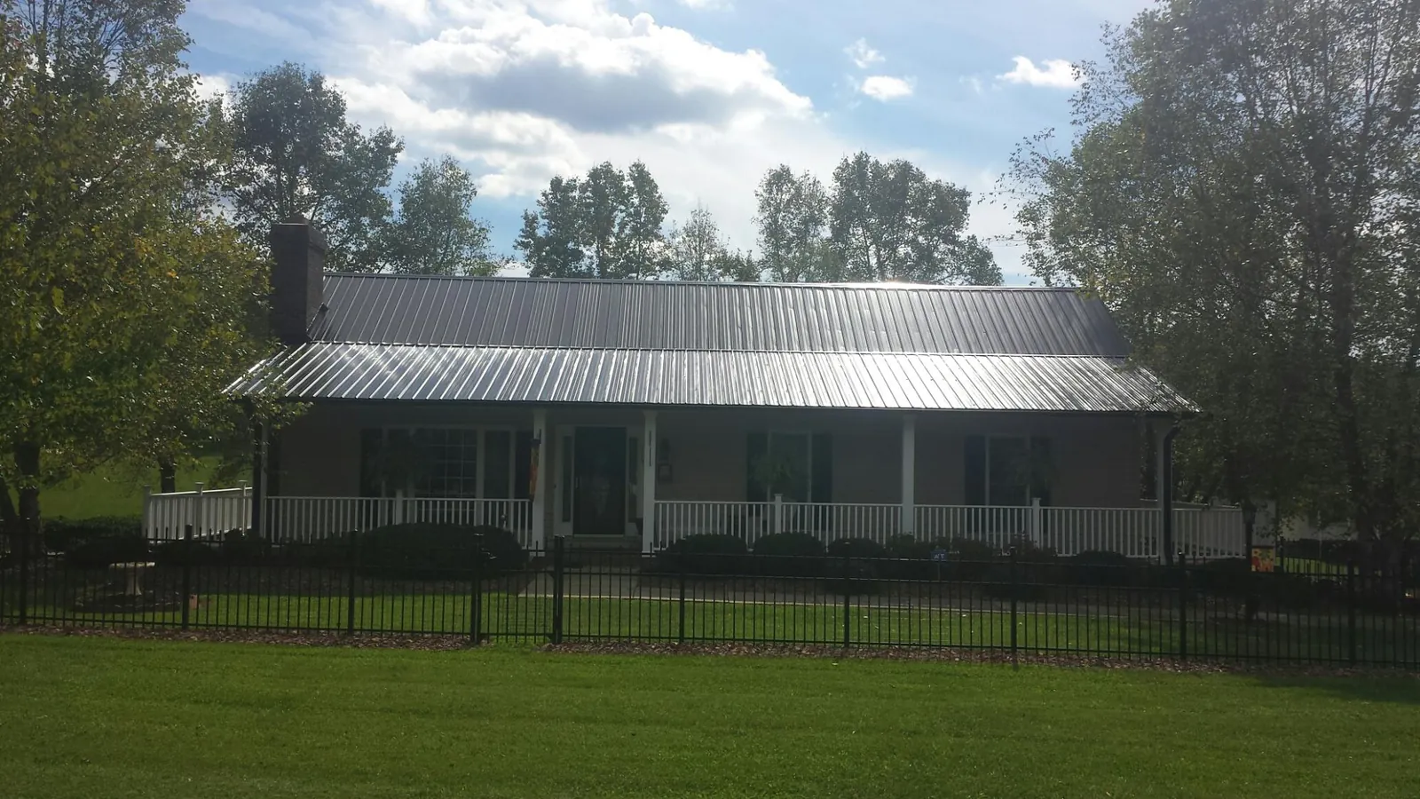 Gray metal roof on a brick ranch with a full width front porch — Gutter Guard Installation work by our crew in Kendallville