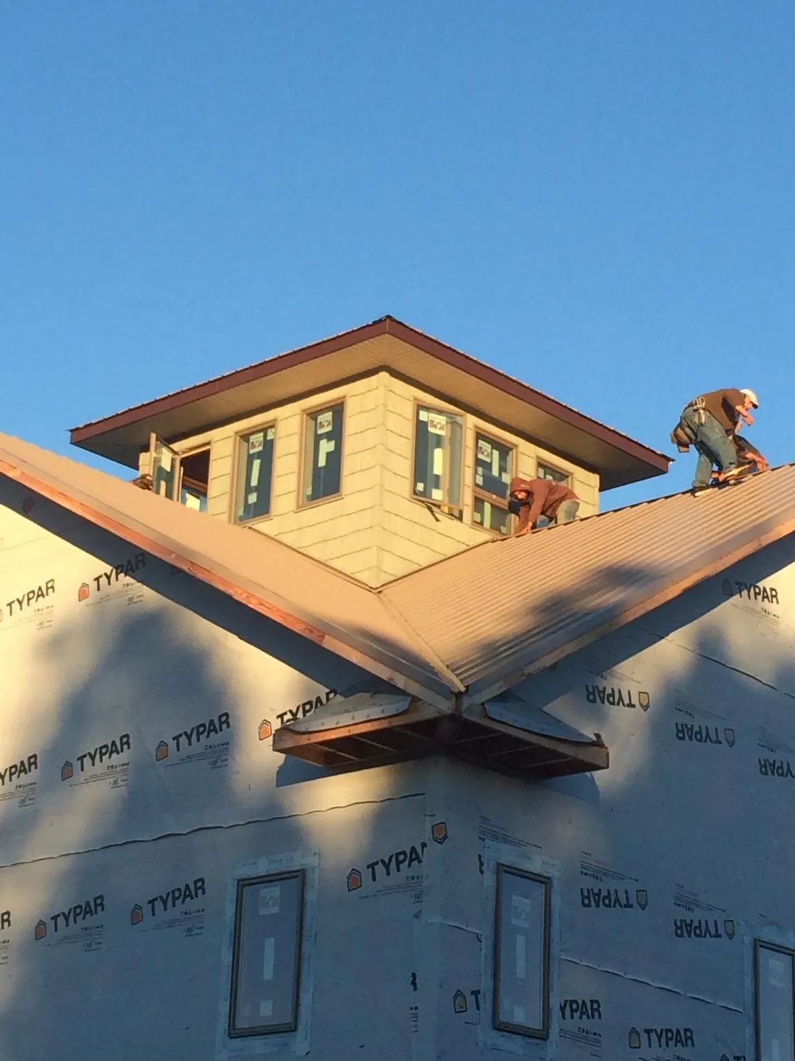 Roofers working around a rooftop cupola on a new metal roof at sunset — Roof Waterproofing in Kendallville by Roofing Brothers